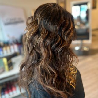 A woman with long wavy hair is wearing a black shirt with the word love on it.