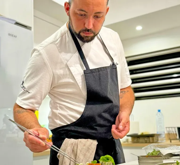 A man in an apron is preparing food in a kitchen.