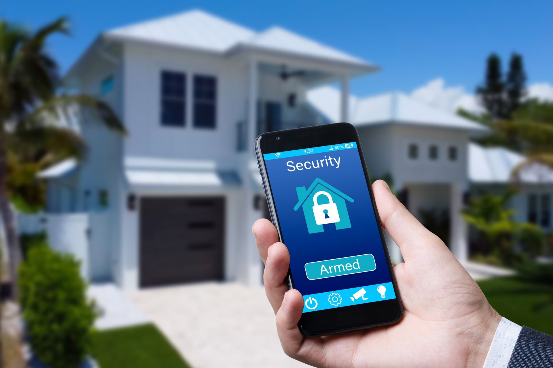Hand holding a smartphone with a security lock app in front of a suburban house