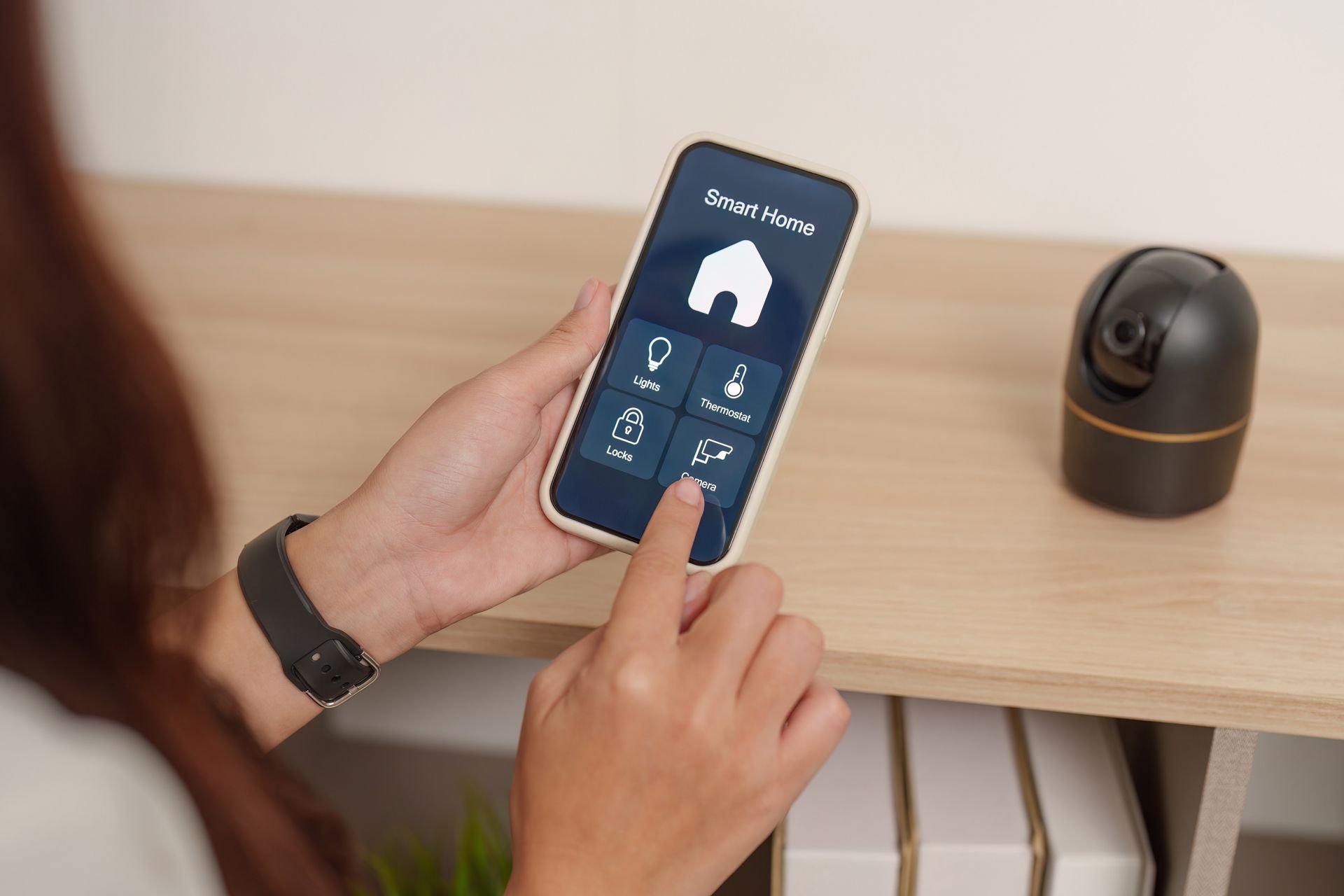 Person using a smartphone app to control a device on a wooden shelf in a home setting