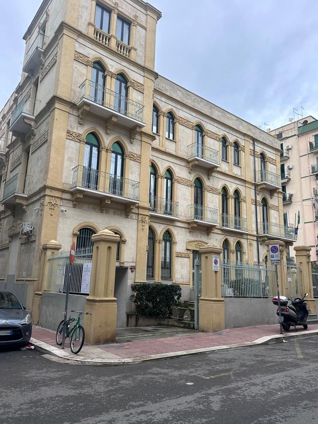 Tetto con pannelli metallici rossi, pannelli solari, camini e palazzi residenziali sullo sfondo.