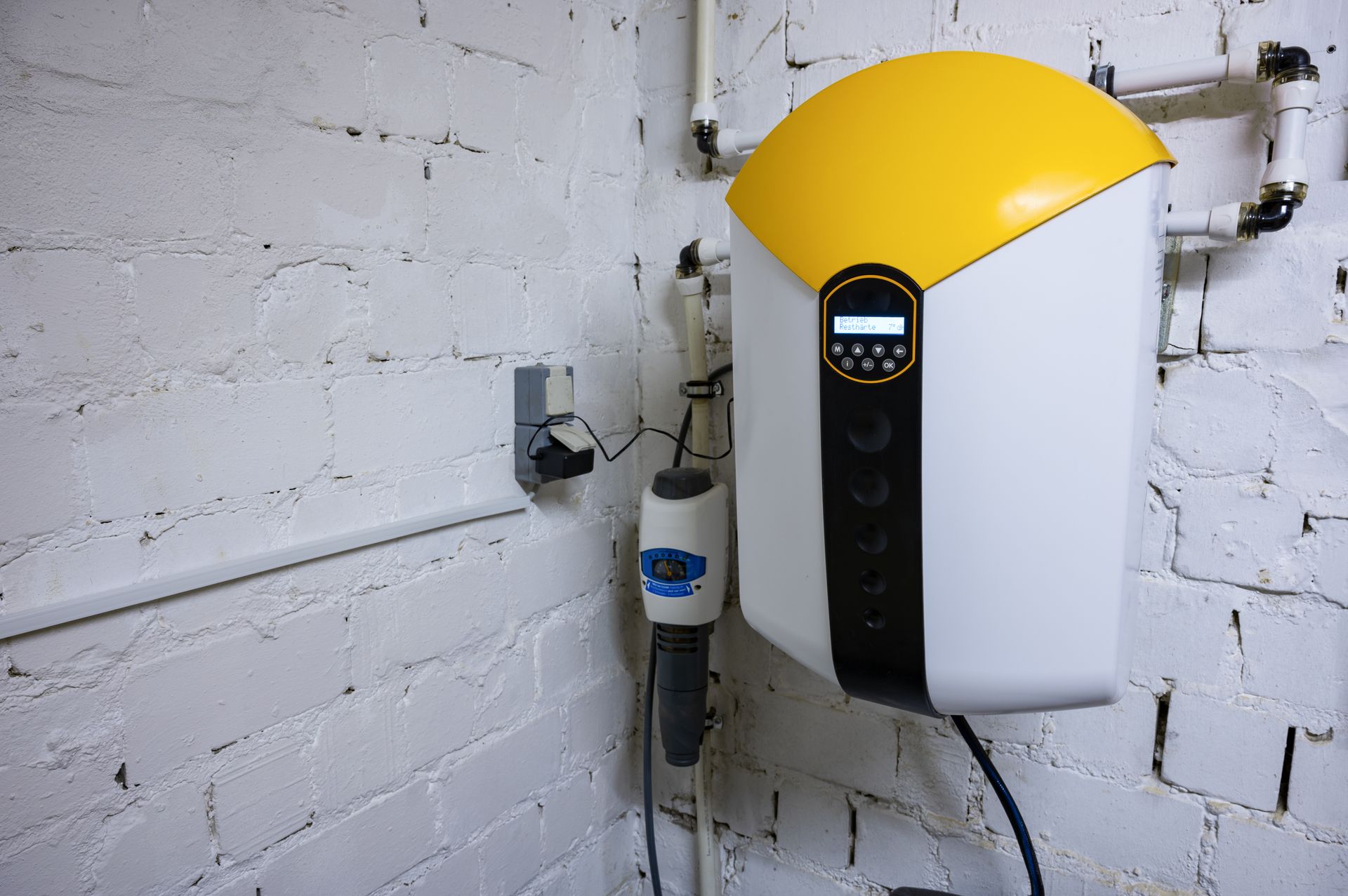 Wall-mounted water softener system connected to residential plumbing lines.