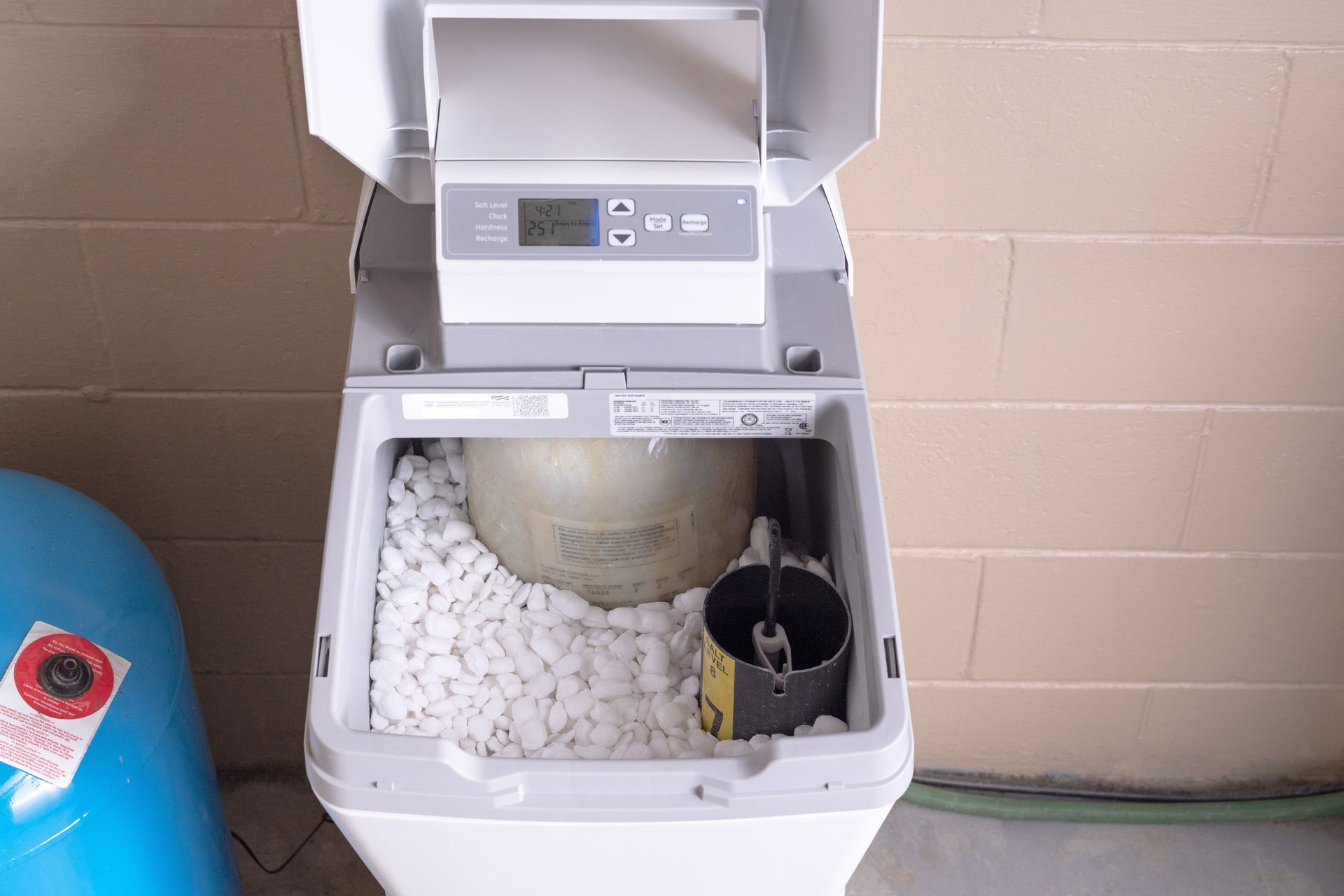Water softener system with an open salt tank filled with pellets and a digital control panel.