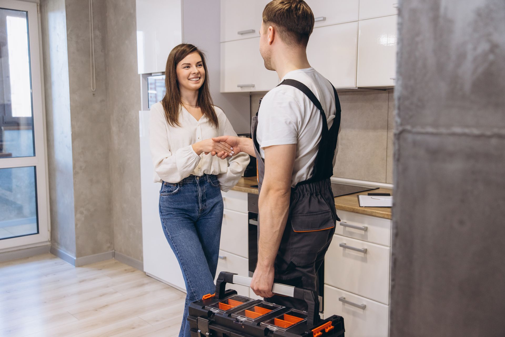 Plumber and homeowner shaking hands after completing plumbing maintenance service.