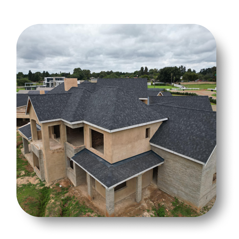 New house under construction with dark gray roof and beige exterior, viewed from above