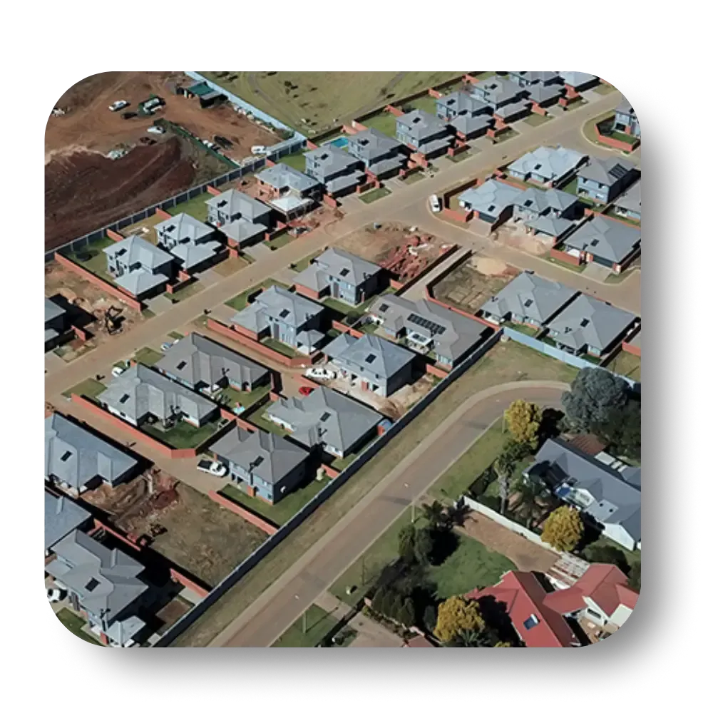 Aerial view of a suburban neighborhood with rows of houses, streets, and construction sites