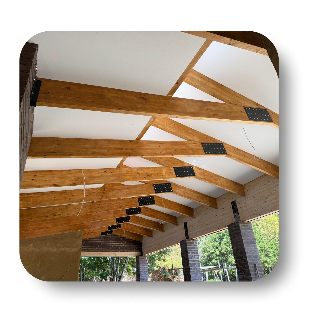 Wood-beam pavilion ceiling with white panels and black metal brackets over brick columns
