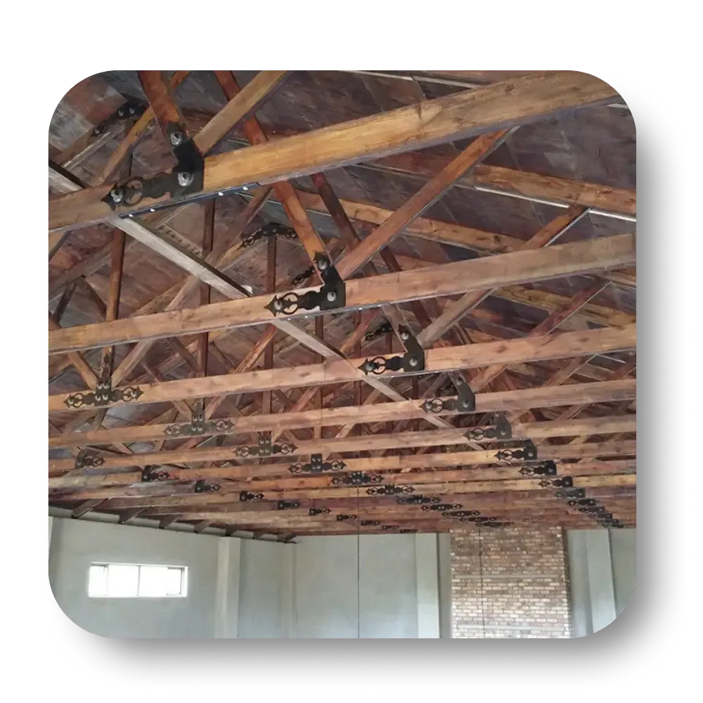 Wooden rafters and beams supporting a roof. Metal connectors are visible throughout.