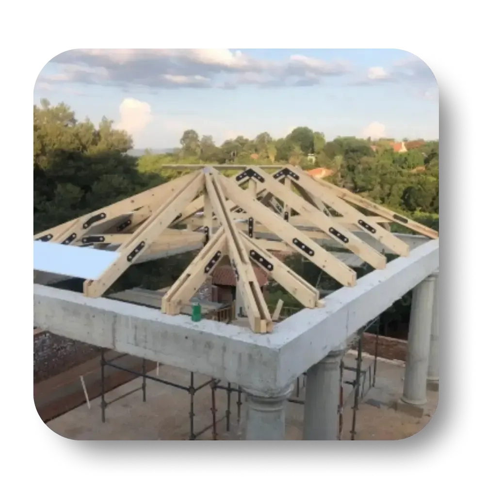 A wooden roof under construction on a white concrete structure, surrounded by scaffolding, trees and sky.