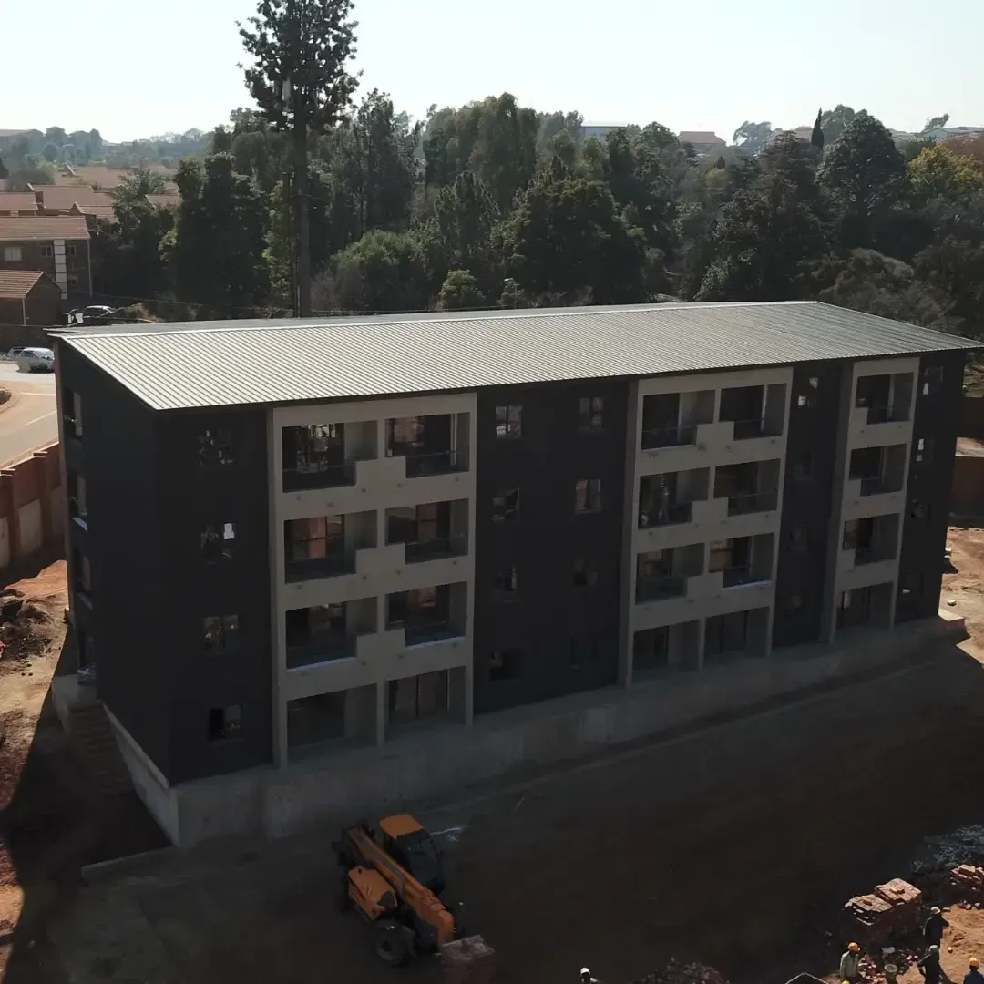 Aerial view of a new four-story apartment building with a construction vehicle in front.