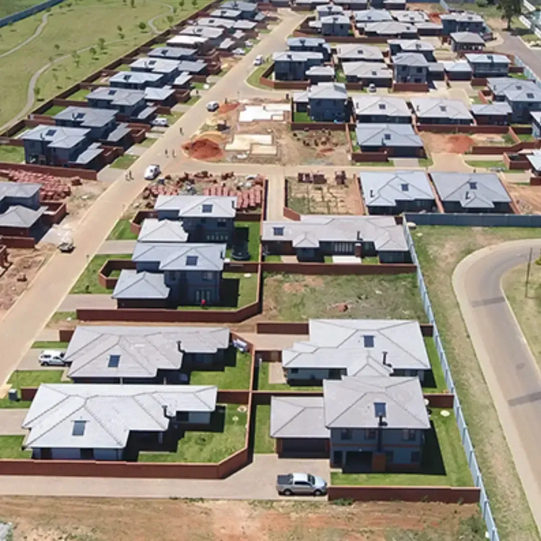 Aerial view of a suburban housing development with rows of new houses, roads, and construction areas.