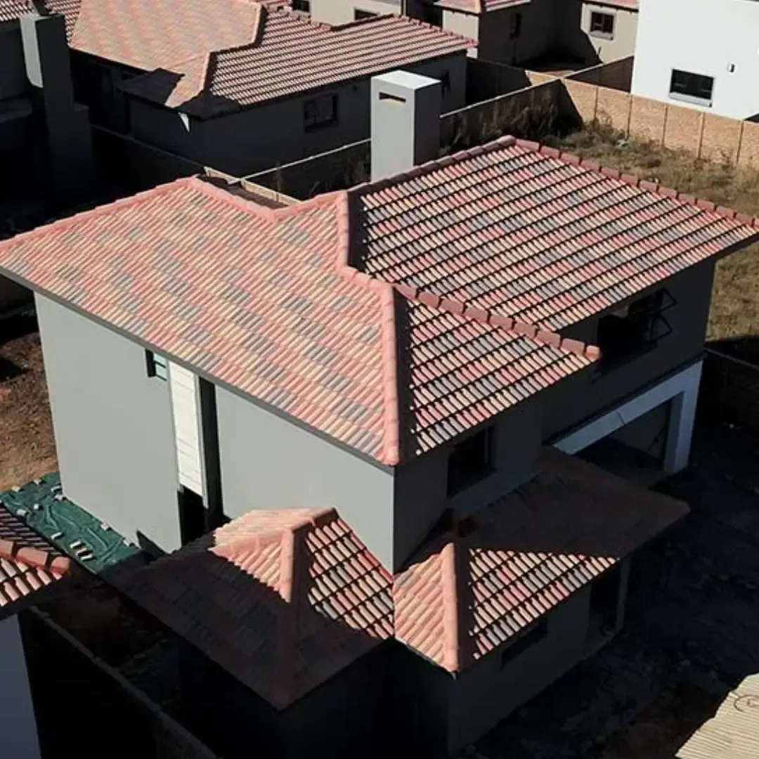 Aerial view of a gray house with red-tiled roofs in a residential neighborhood