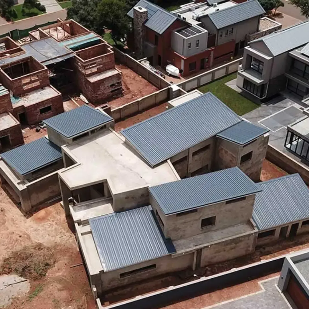 Aerial view of several modern houses with gray metal roofs in a residential area under construction.