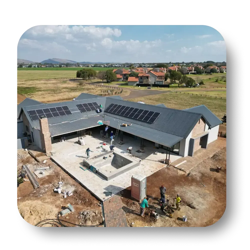 Aerial view of a new house under construction with solar panels in a rural landscape.