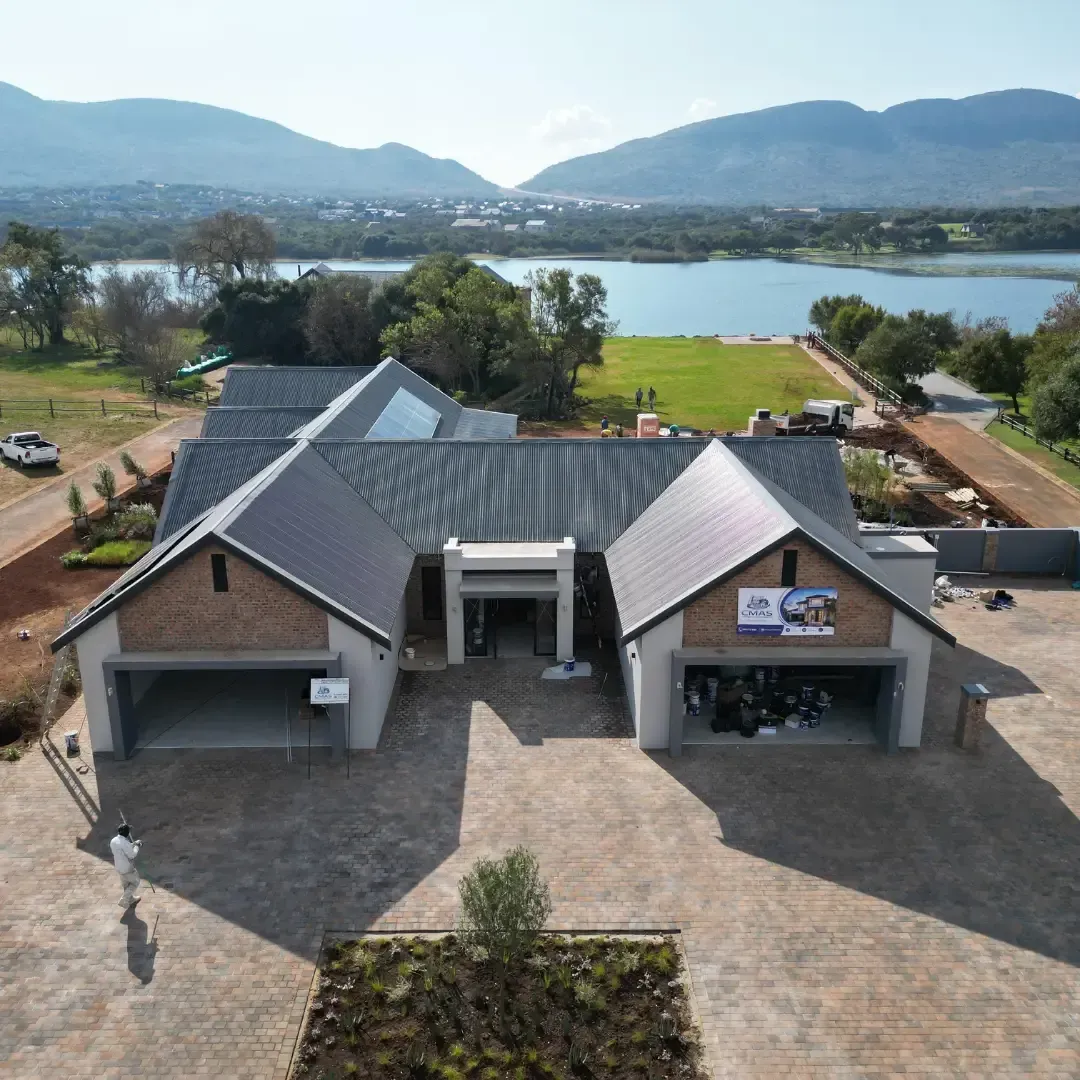 Aerial view of a brick building with a lake and mountains in the background
