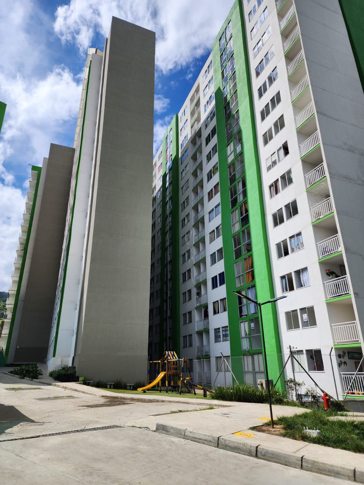 Edificios de apartamentos de gran altura con fachadas verdes y blancas bajo un cielo nublado.
