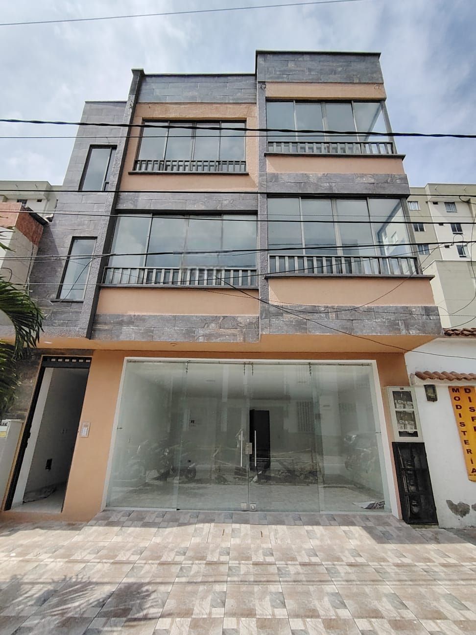 Casa adosada moderna de varias plantas con balcones y planta baja con fachada de cristal, actualmente en construcción.