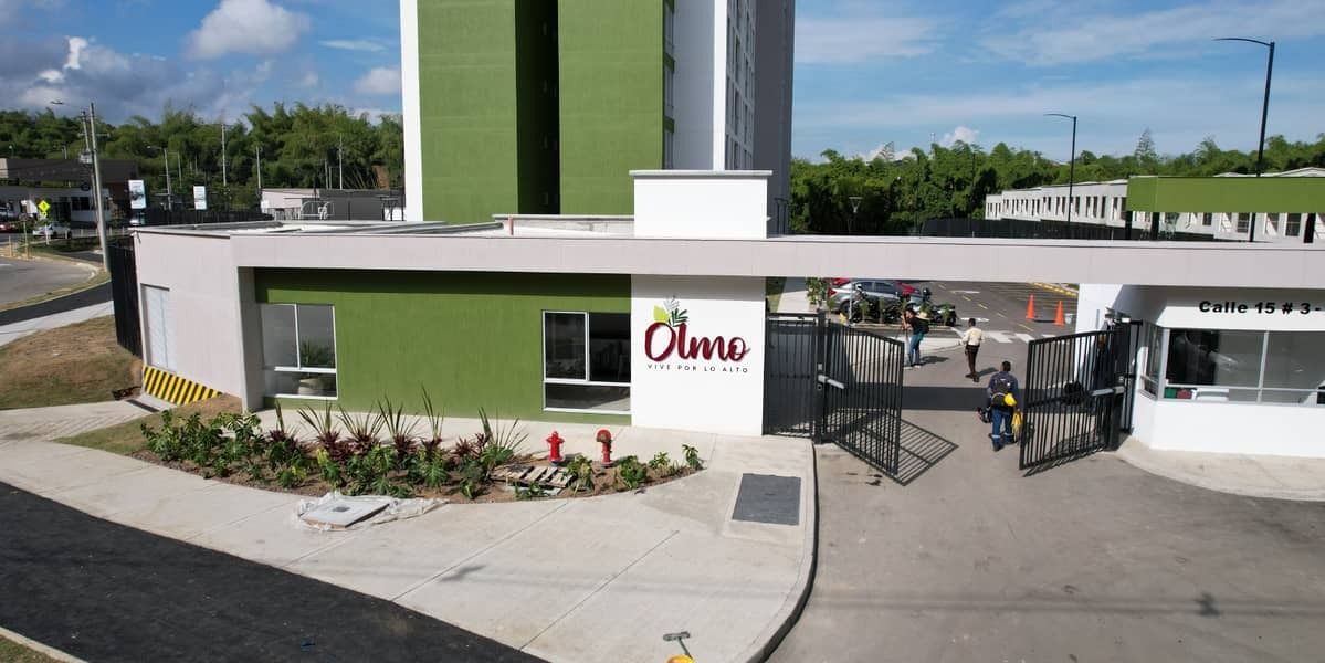 Pequeña cafetería con fachada verde y mesas al aire libre en un día soleado.