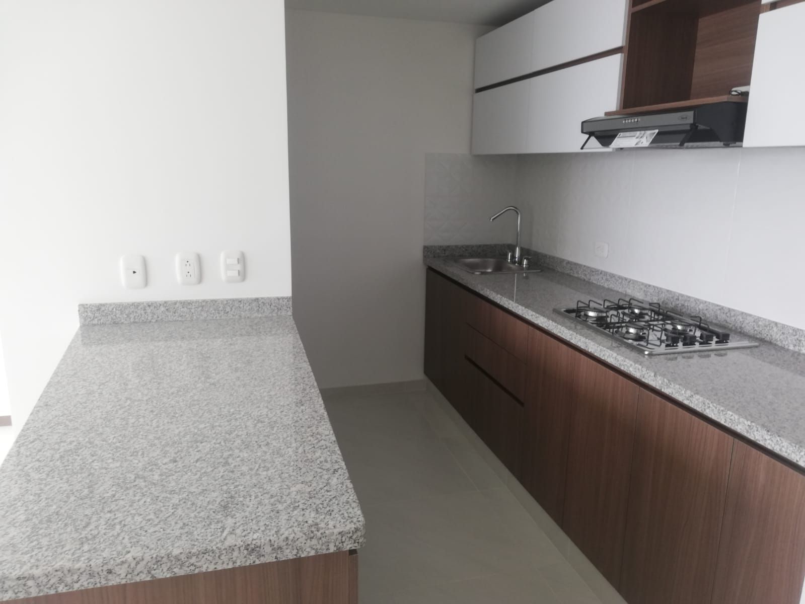 Cocina moderna con encimeras grises, armarios marrones y un fregadero a lo largo de una pared.