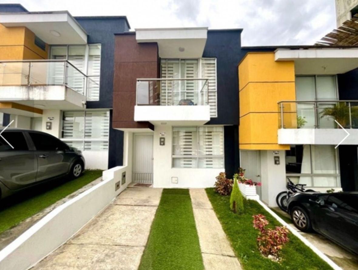 Hilera de casas adosadas modernas con fachadas blancas, azul marino y amarillas, pequeños jardines delanteros.