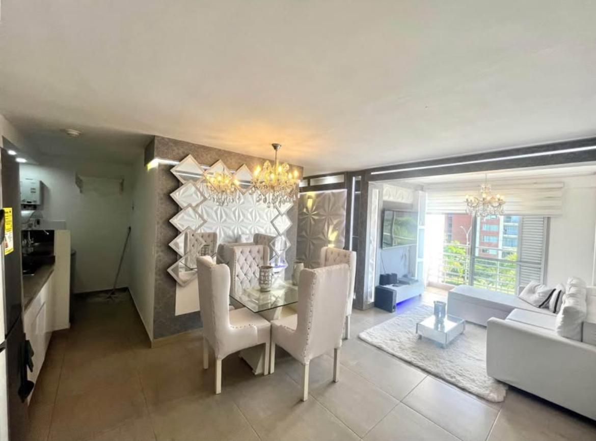 Salón-comedor moderno con muebles blancos, lámpara de araña y grandes puertas correderas de cristal.