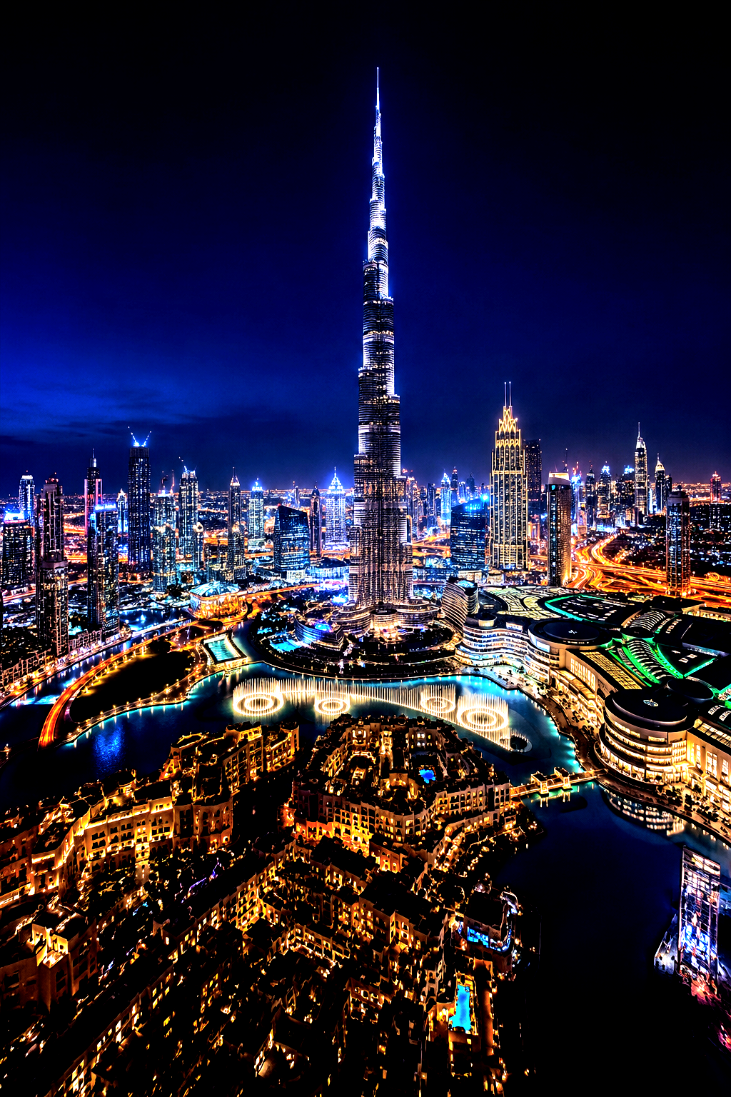 Night view of Dubai skyline with the illuminated Burj Khalifa towering over city lights and fountains