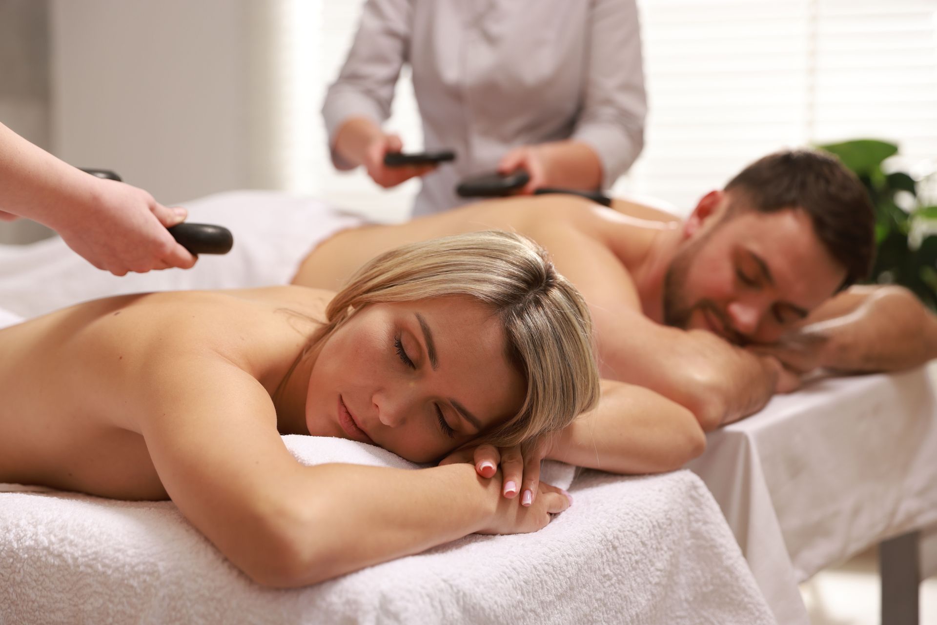 Two people receiving a back massage on tables in a spa treatment room