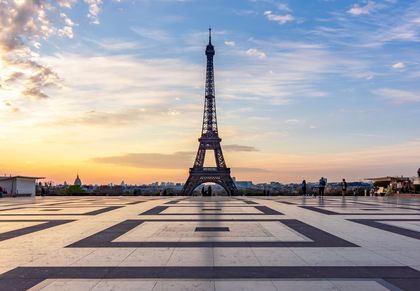 Eiffel Tower at sunset over a wide stone plaza with a pastel sky