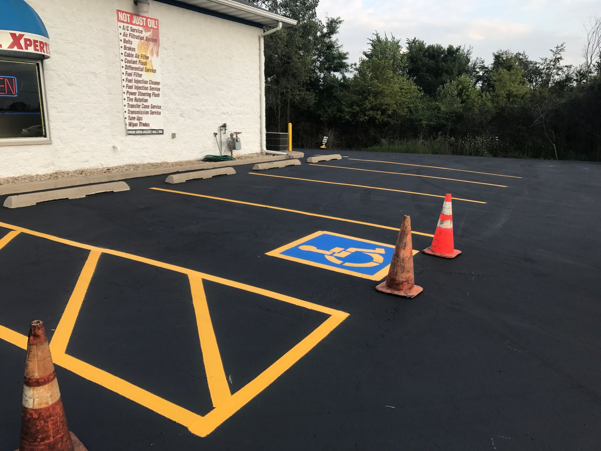 Parking lot with fresh yellow lines and a handicap space marked. Orange cones present.