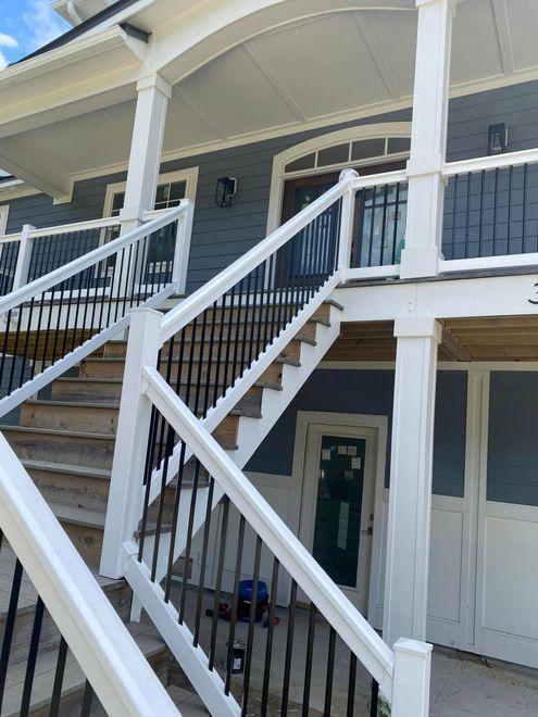 Front porch of a house with white railings, blue siding, and stairs leading up to the entrance.