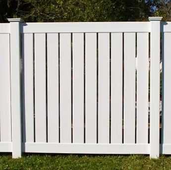 White wooden fence with vertical slats and posts in a grassy yard
