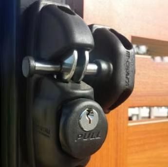 Close-up of a black door lock with a silver key inserted in a wooden door.
