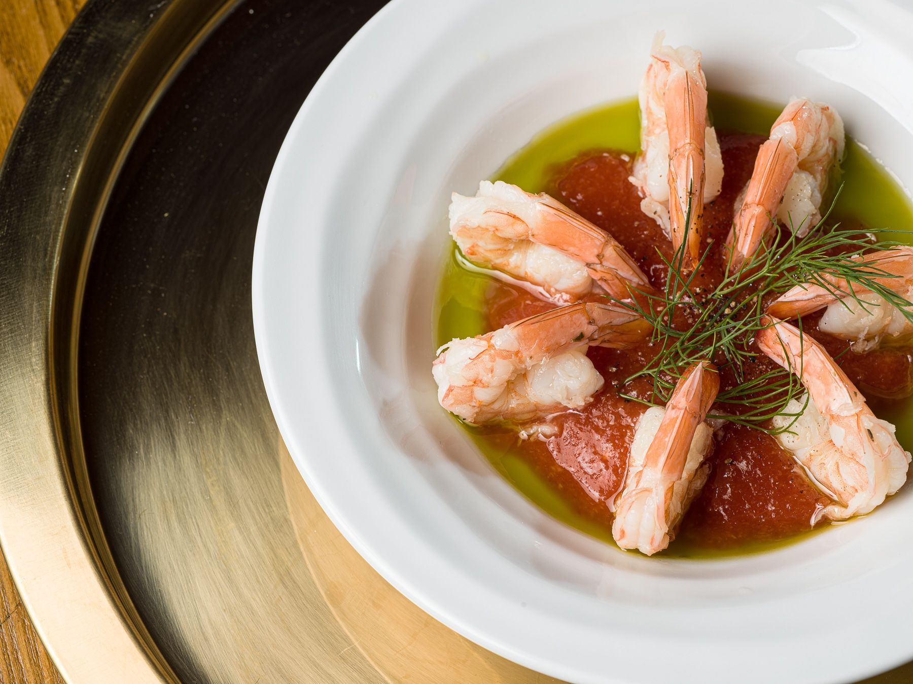 A white plate topped with shrimp and grapefruit on a table