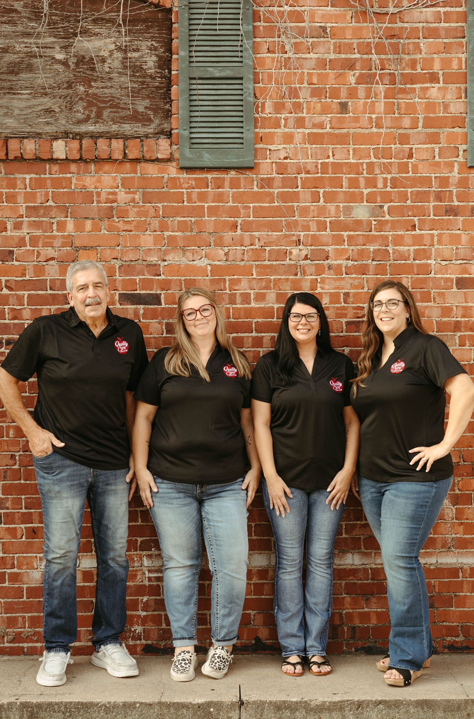 A group of people are standing in front of a brick wall.
