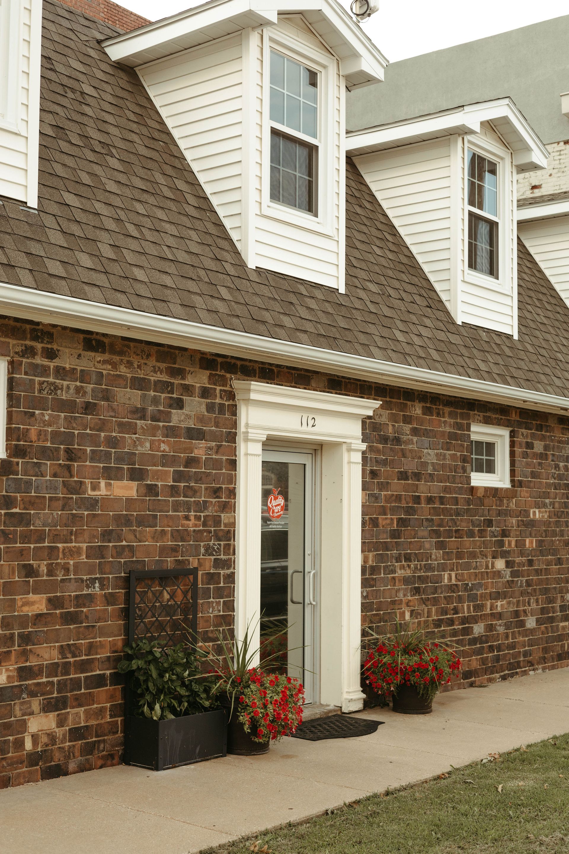 A brick house with a white trim and a brown roof
