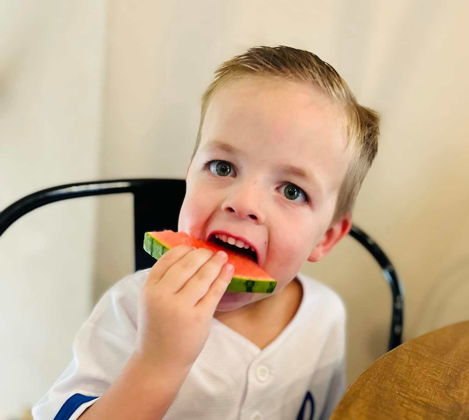 A young boy is eating a slice of watermelon