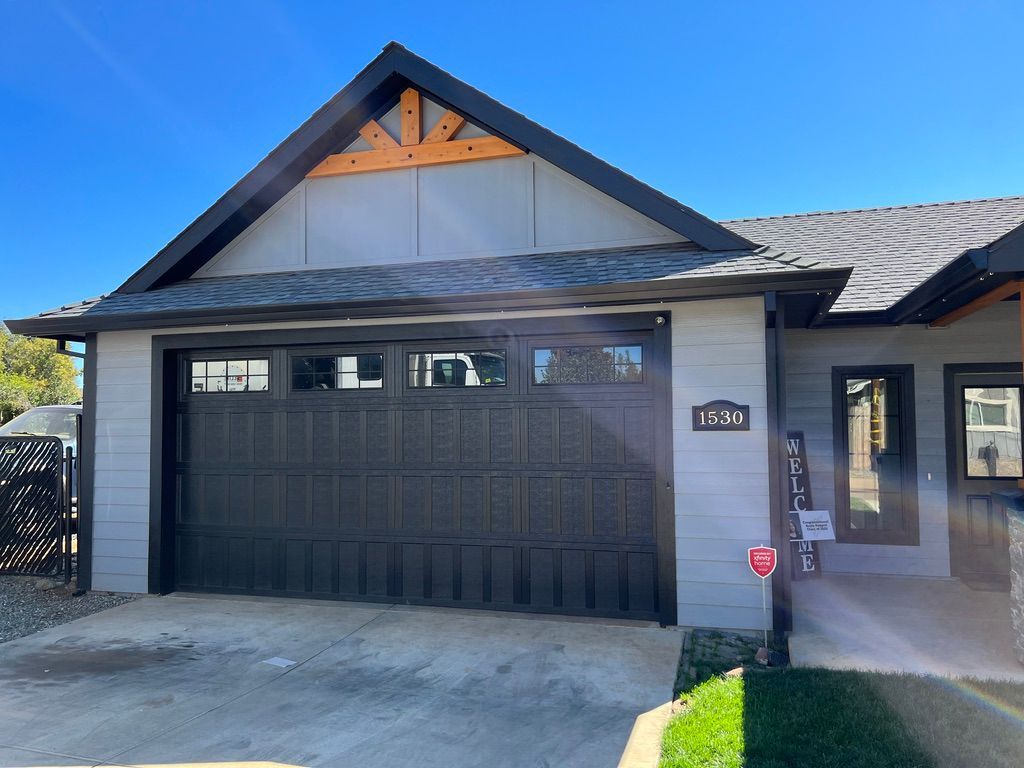 Front view of a house with a black double garage door and a covered entryway