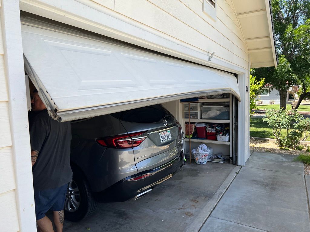 Garage door bent upward, trapping an SUV inside a garage with a person standing beside it.