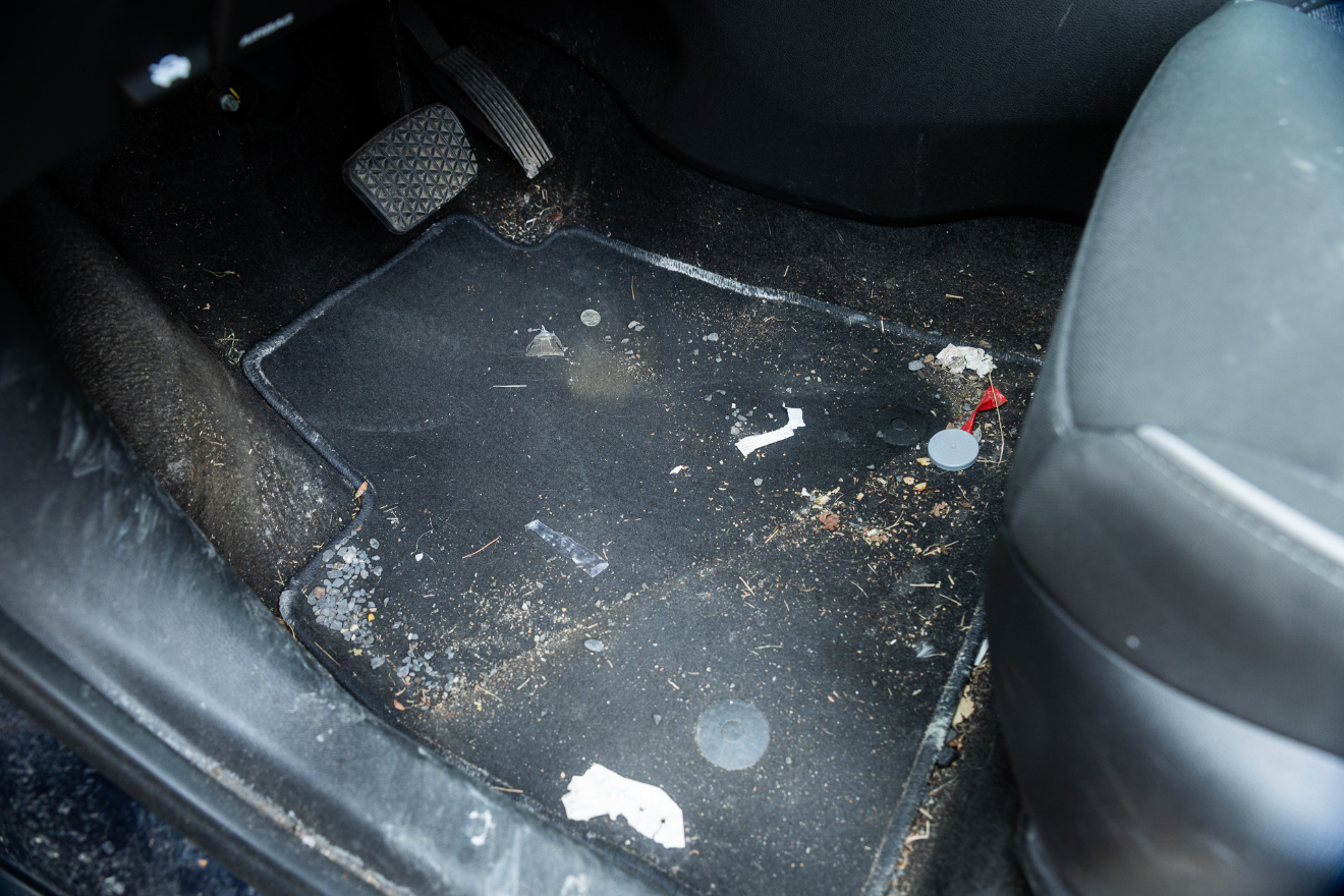Dirty car floor with scattered debris and stains beside a seat