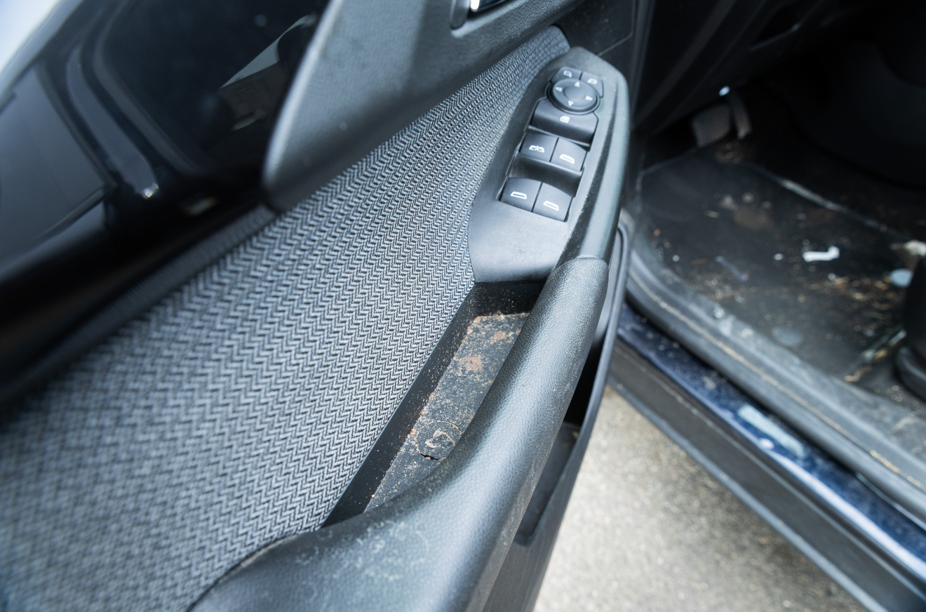 Close-up of a car door interior with window and lock controls on gray fabric trim