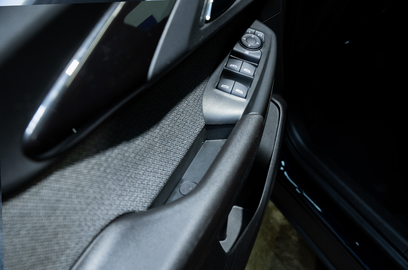 Close-up of a car door interior with power window and lock controls on a black panel