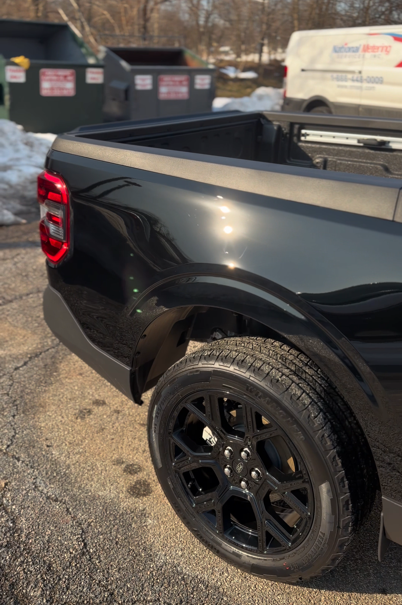 Person polishing a black car hood with a buffer in a garage
