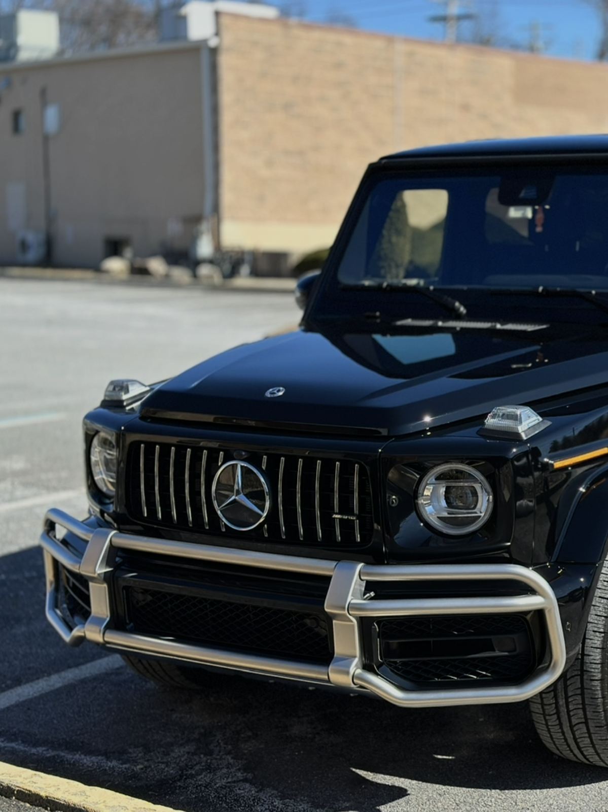 Black Mercedes-Benz SUV parked outdoors in sunlight, front view with chrome grille and bumper.