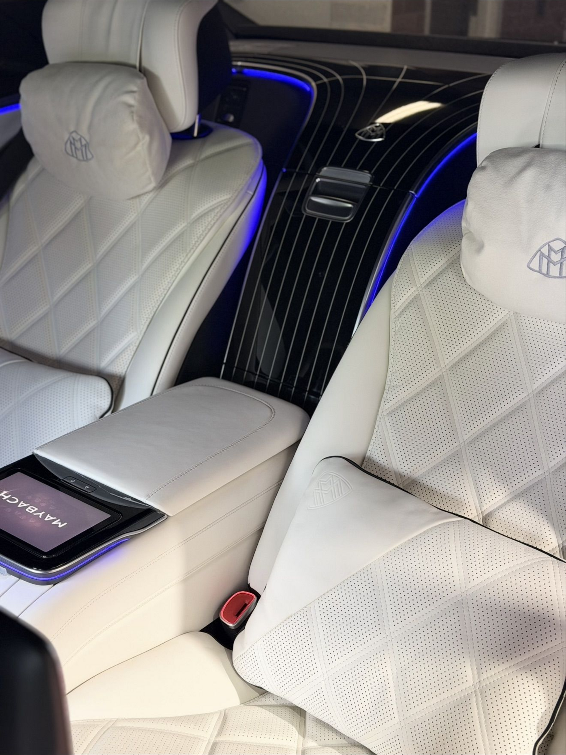 Luxury car interior with white seats, black center console, and blue ambient lighting