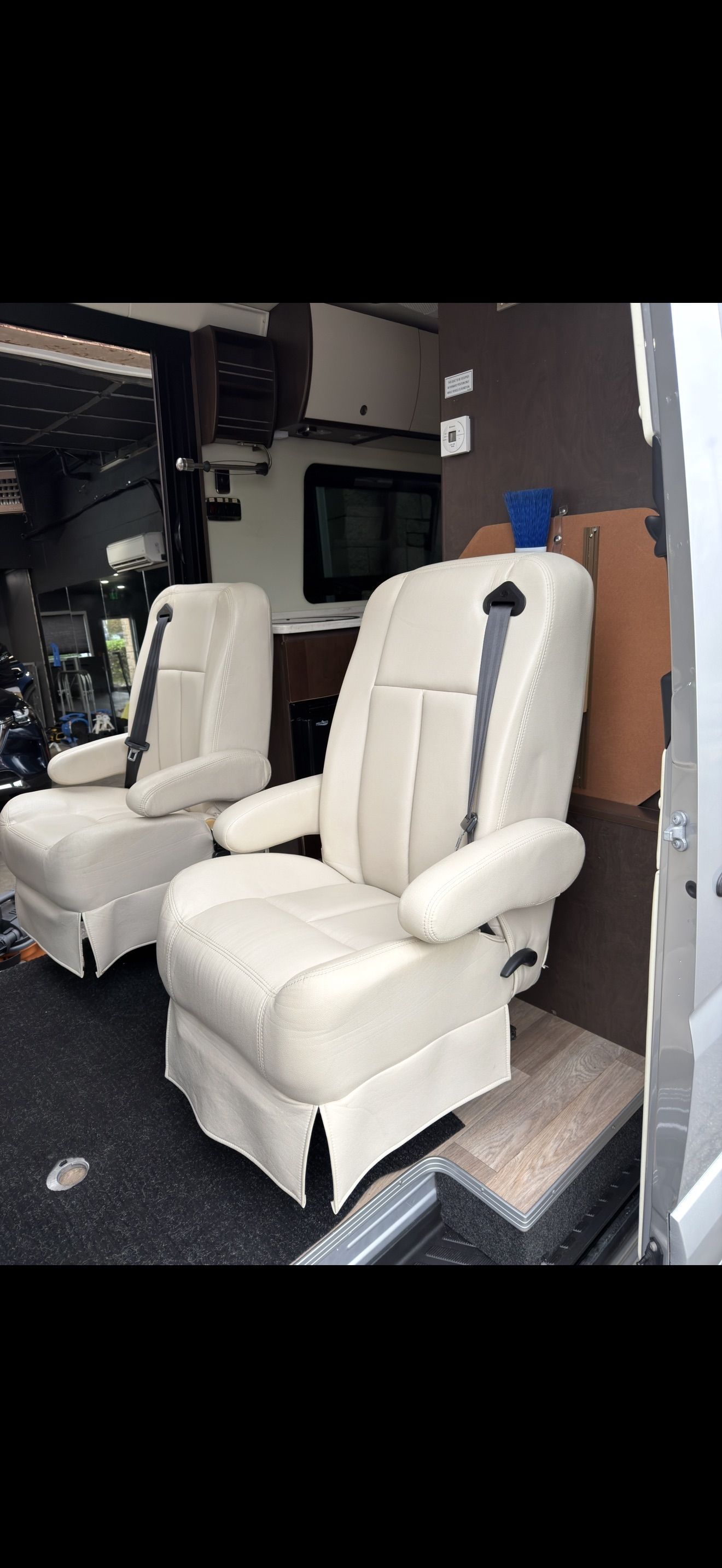 Two cream-colored recliner chairs in a store or workshop, one facing forward, one angled left.