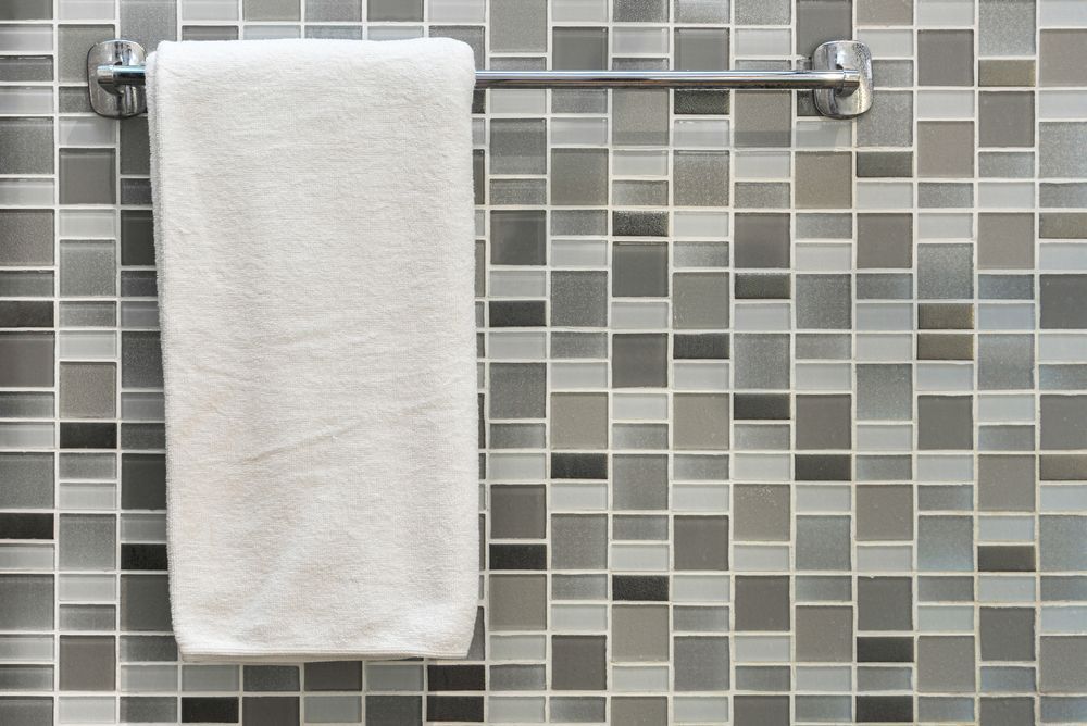 A white towel is hanging on a towel rack on a tiled wall. — Tuncurry Washerteria In Diamond Beach, NSW