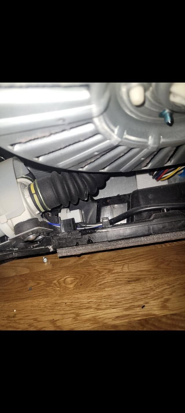 Close-up of a gray vented interior with black tubing and wires above a wooden surface