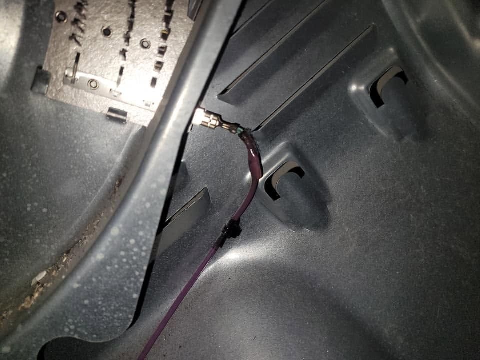 Close-up of a gray metal interior panel with a purple wire running along the seam