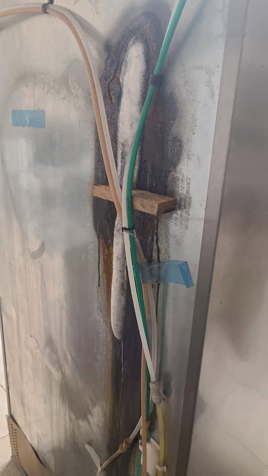 Cables taped to a wall-mounted metal bracket with blue tape and brown insulation material