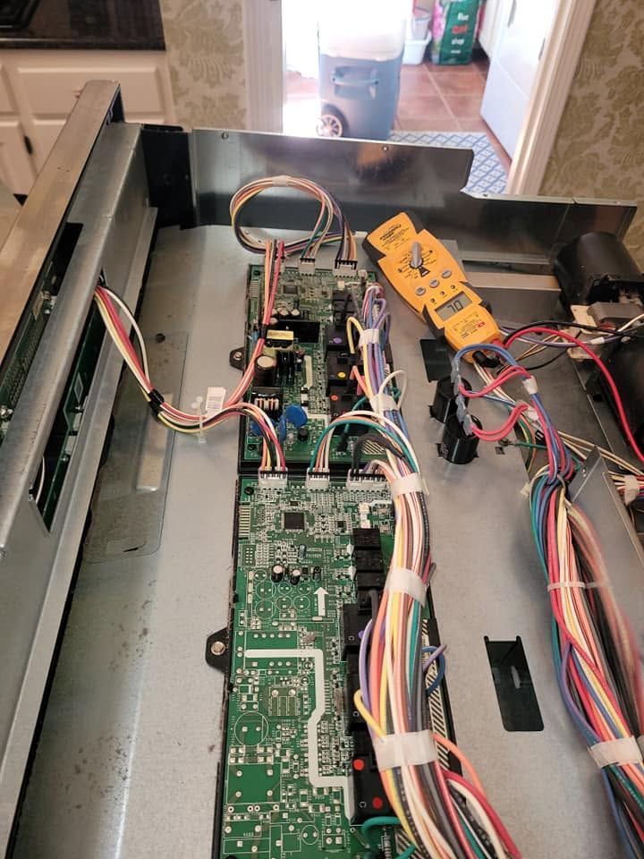 Open electronic device with circuit boards, wires, and a yellow multimeter inside a metal chassis.